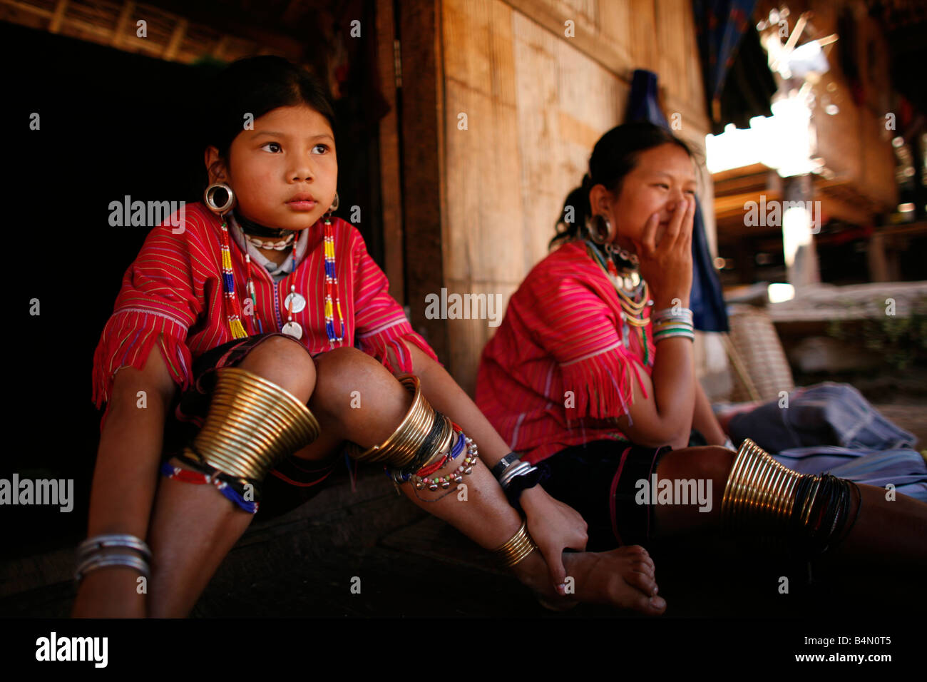 Les jeunes filles à l'extérieur d'une maison dans le camp de réfugiés, environ 300 réfugiés birmans en Thaïlande sont membres de communautés indigènes Longnecks groupe connu sous le nom de la plus grande des trois villages où l'Longnecks live est appelé Nai Soi situé près de la ville de Mae Hong Son Longnecks porter des bagues métalliques sur le cou qui poussent la clavicule fait et étendre le cou Ils sont une attraction touristique touristes visitent Nai Soi pour prendre des photos de l'Longnecks et acheter leur artisanat Les villages sont critiqués par les organisations des droits de l'homme comme les zoos Banque D'Images