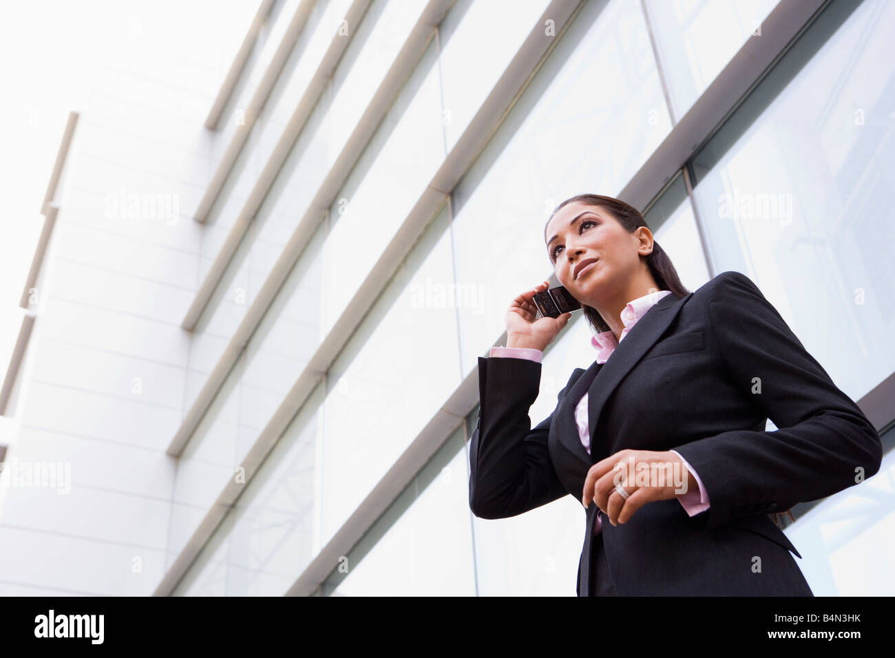 Businesswoman standing en plein air en s'appuyant sur téléphone cellulaire (high key/focus sélectif) Banque D'Images