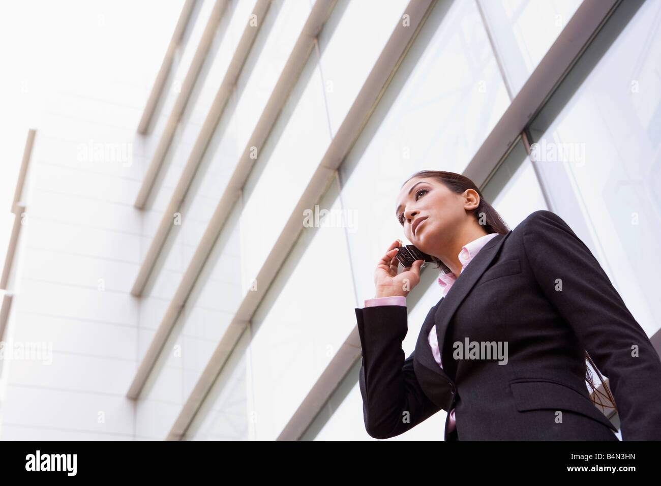 Businesswoman standing en plein air en s'appuyant sur téléphone cellulaire (high key/focus sélectif) Banque D'Images