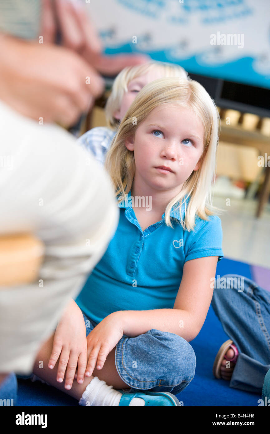 Student in class sitting on floor looking at enseignant (selective focus) Banque D'Images