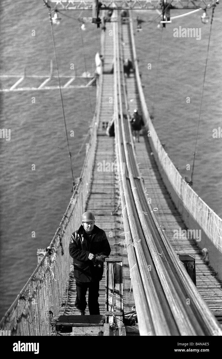 Le Forth Road Bridge est un pont suspendu à la différence du pont ferroviaire en porte-à-faux, Plusieurs propositions ont été rejetées avant la Mott Hay et Anderson design a été choisi c'est le premier pont suspendu de longue portée au Royaume-Uni d'autres ont bien sûr suivi le Severn Bridge et le Humber Bridge le Forth Road Bridge contient 39 000 tonnes d'acier le tours de 494 pieds au-dessus des fondations en béton et il a fallu un effectif de 300 à seulement trois ans et demi pour terminer la construction des ponts Workman Juin 1962 1960 Banque D'Images