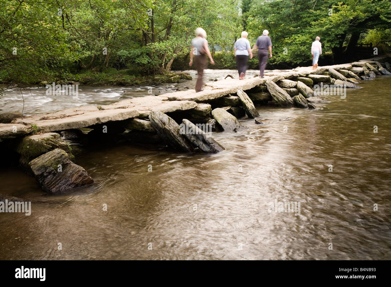 Touristes traversant Tarr Étapes pack horse bridge près de Dulverton Exmoor National Park North Devon Banque D'Images