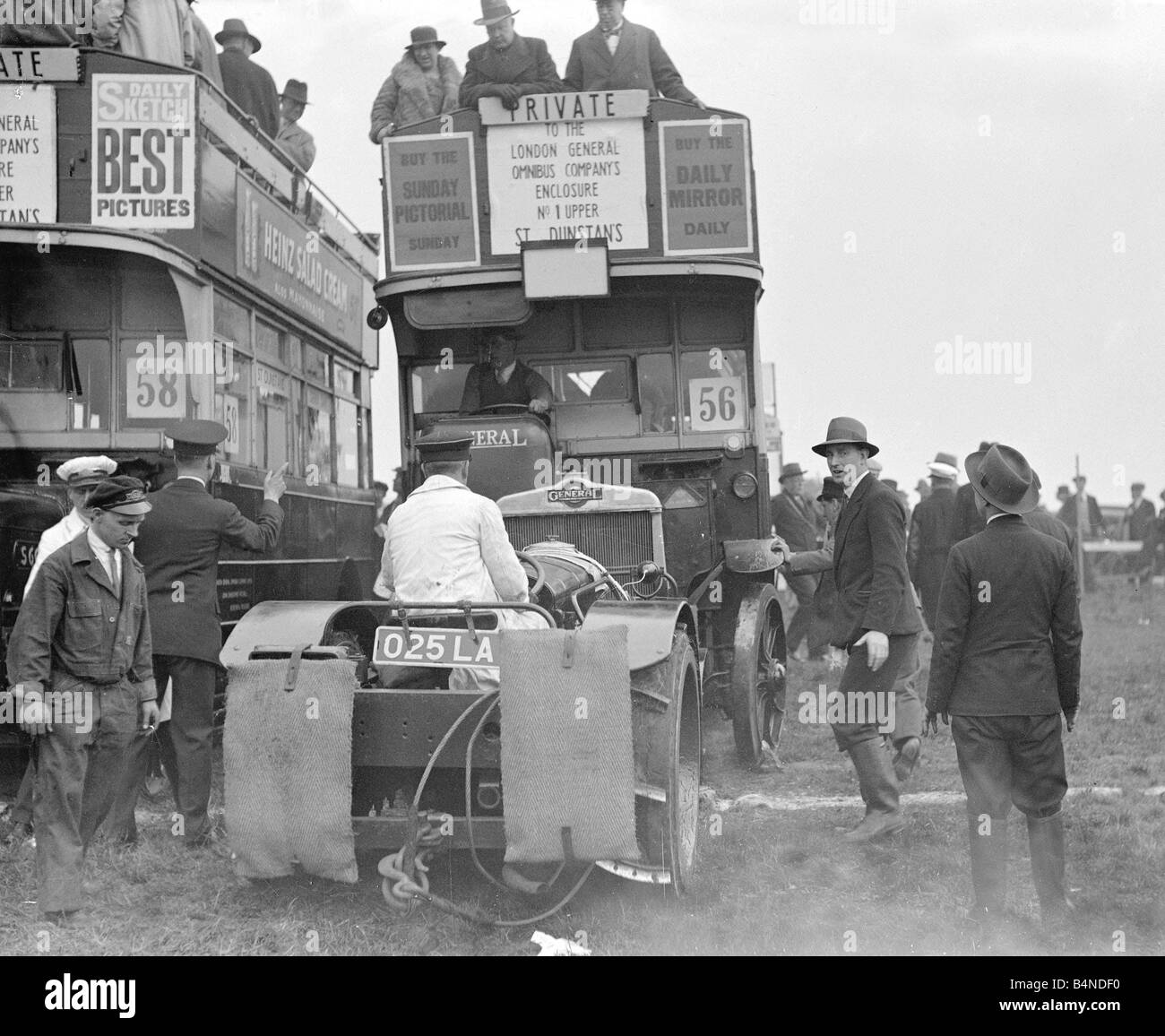 Courses Epson Transports Bus à Impériale vers 1935 Un autobus de transfert à la courses d'Epsom se bloque dans le sol mou et un tracteur est appelé pour aider le double decker bus de s'il sort les gens sur le pont supérieur de regarder par-dessus au-dessous du personnel d'essayer de déplacer le bus Banque D'Images