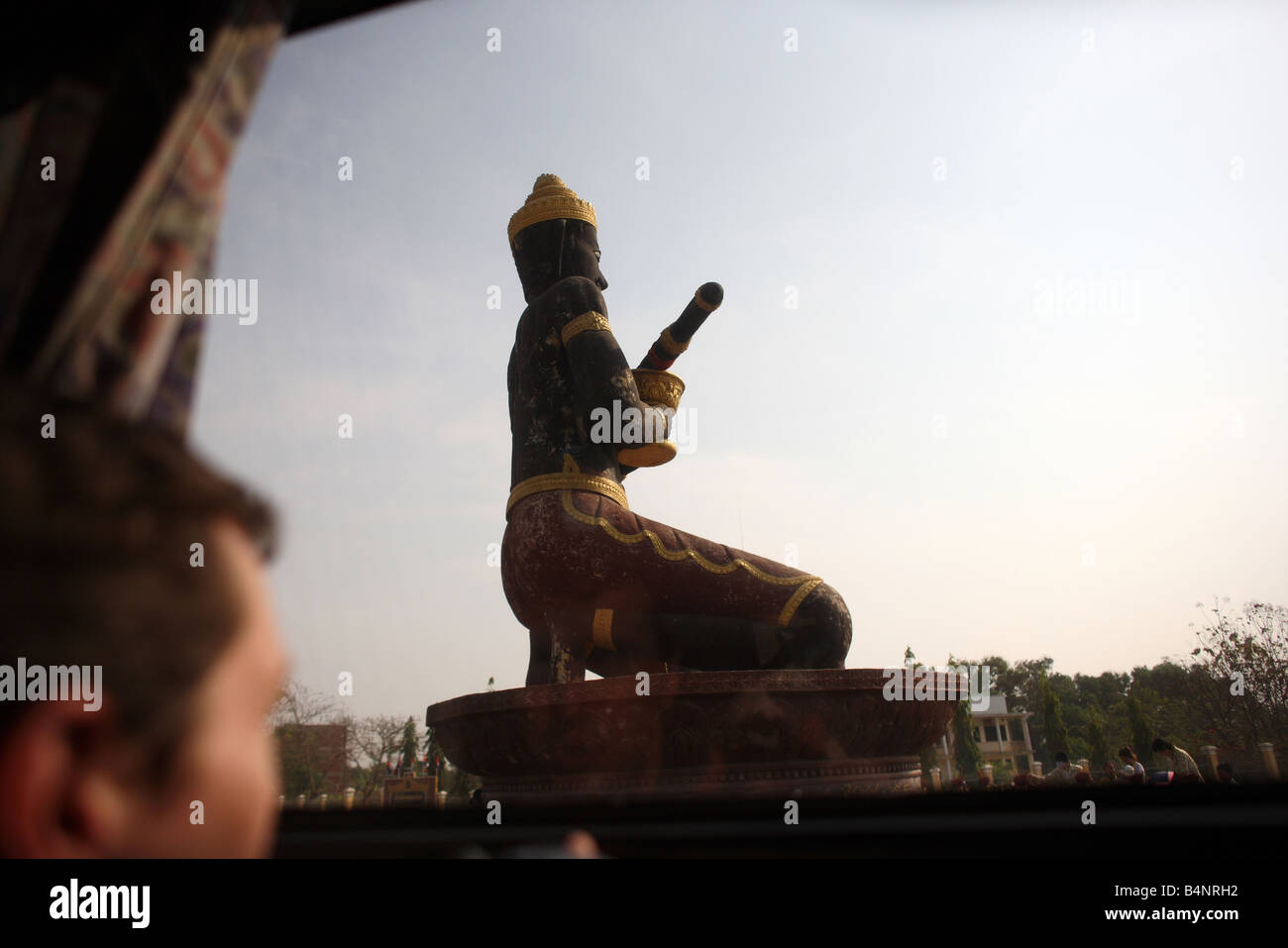 Les touristes à la recherche at statue à Battambang, Cambodge, par une fenêtre de l'autobus Banque D'Images