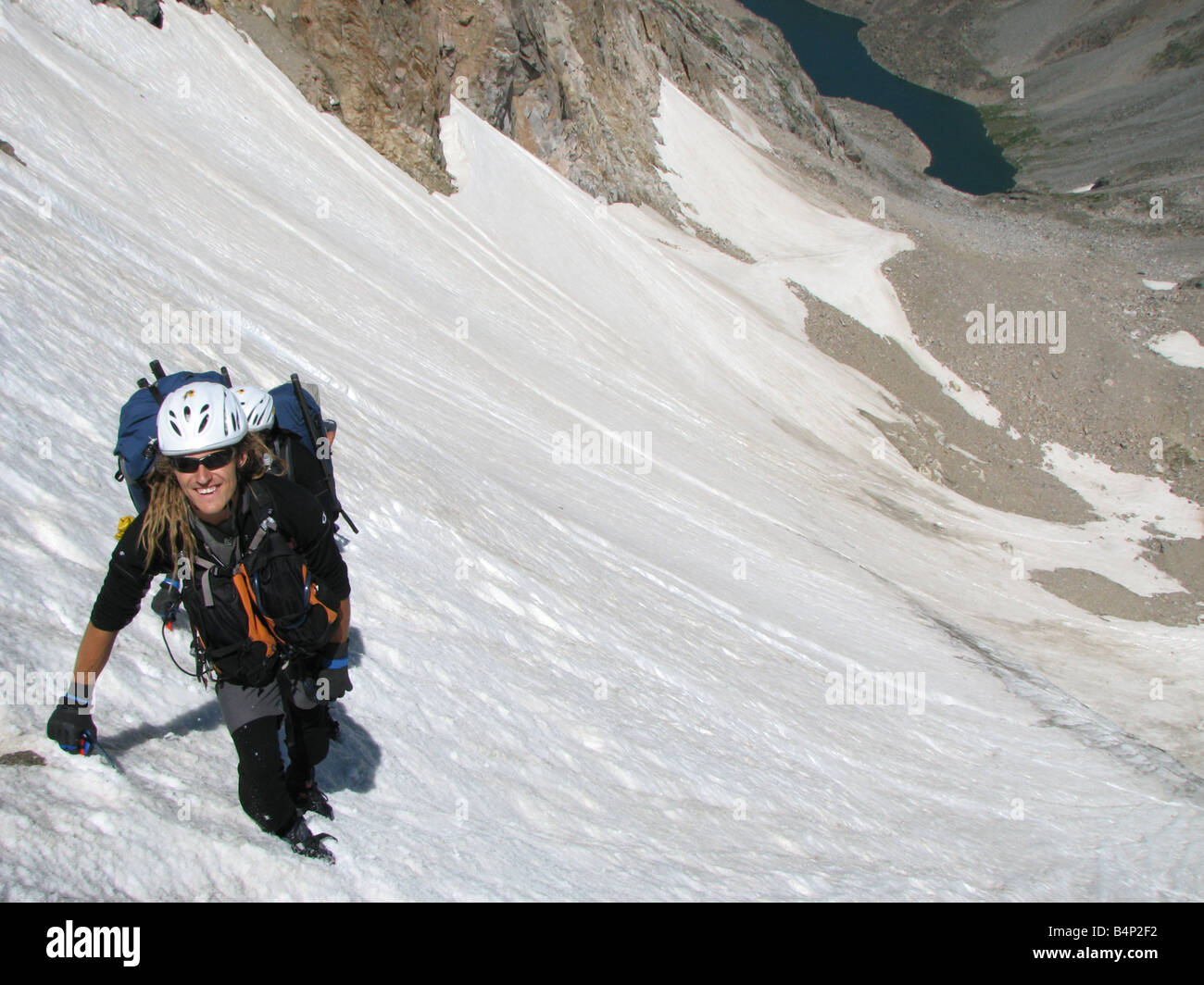 Un homme se hisse au sommet du glacier sur le côté nord de Granite Peak suivie de près par ses compagnons qui sont à peine visibles Banque D'Images