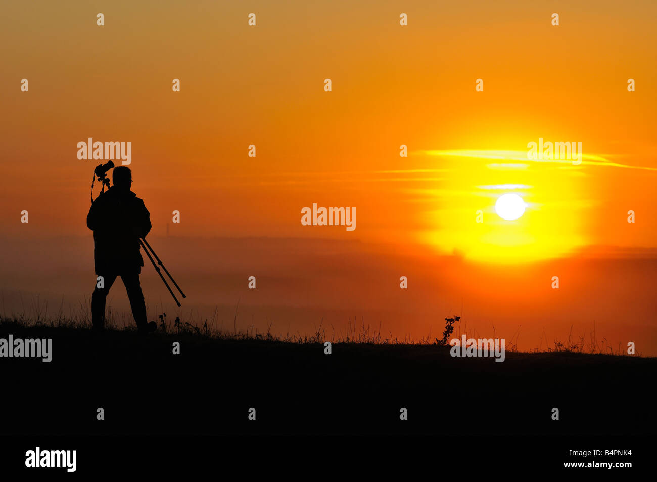 Photographe dans le matin au lever du soleil avec trépied Banque D'Images