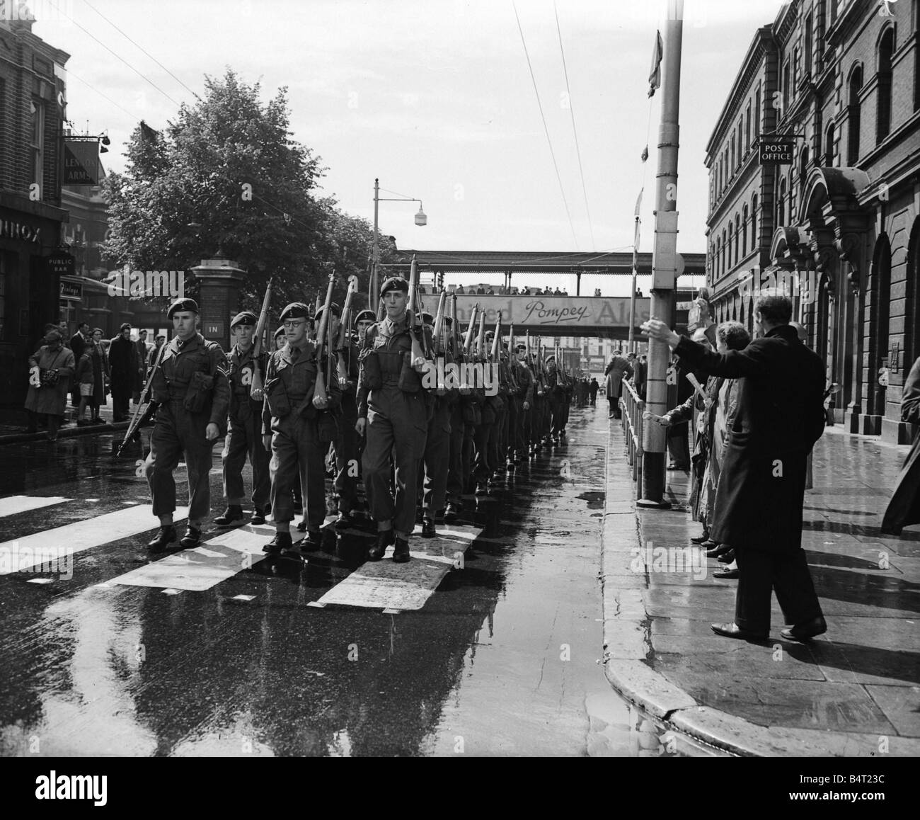 Crise de Suez 1956 personnes dans les rues alors que les troupes de l'onde de plaisir et forme mars Portsmouth Gare aux quais où ils vont se lancer sur le porte-avions HMS Theseus pour le Moyen-Orient Banque D'Images