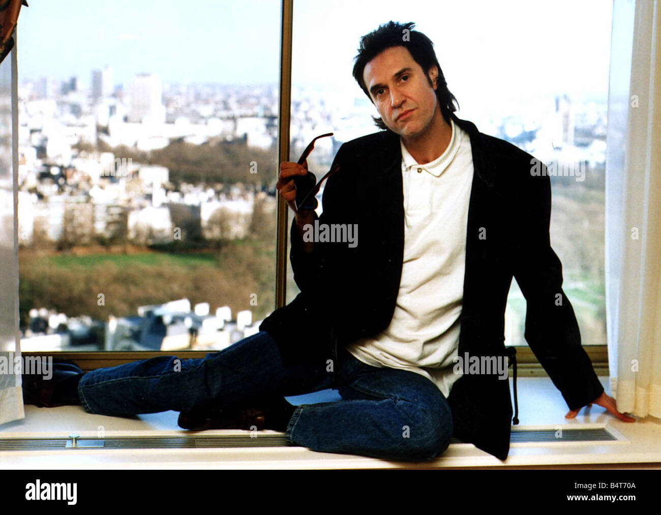 Ray Davies The Kinks pop singer assis sur le rebord de fenêtre de bureau Mars 1990 Banque D'Images