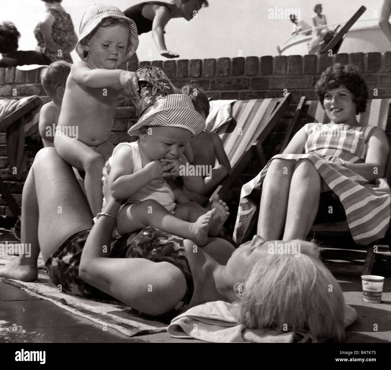 Le soleil chaud et ensoleillé météo Enfants jouant au soleil 2 bébés assis sur leur mère pendant qu'elle soleil 0412 Daily Mirror 1963 mirrorpix030606 Banque D'Images Le soleil chaud et ensoleillé météo Enfants jouant au soleil 2 bébés assis sur leur mère pendant qu'elle soleil 0412 Daily Mirror 1963 mirrorpix030606 Banque D'Images