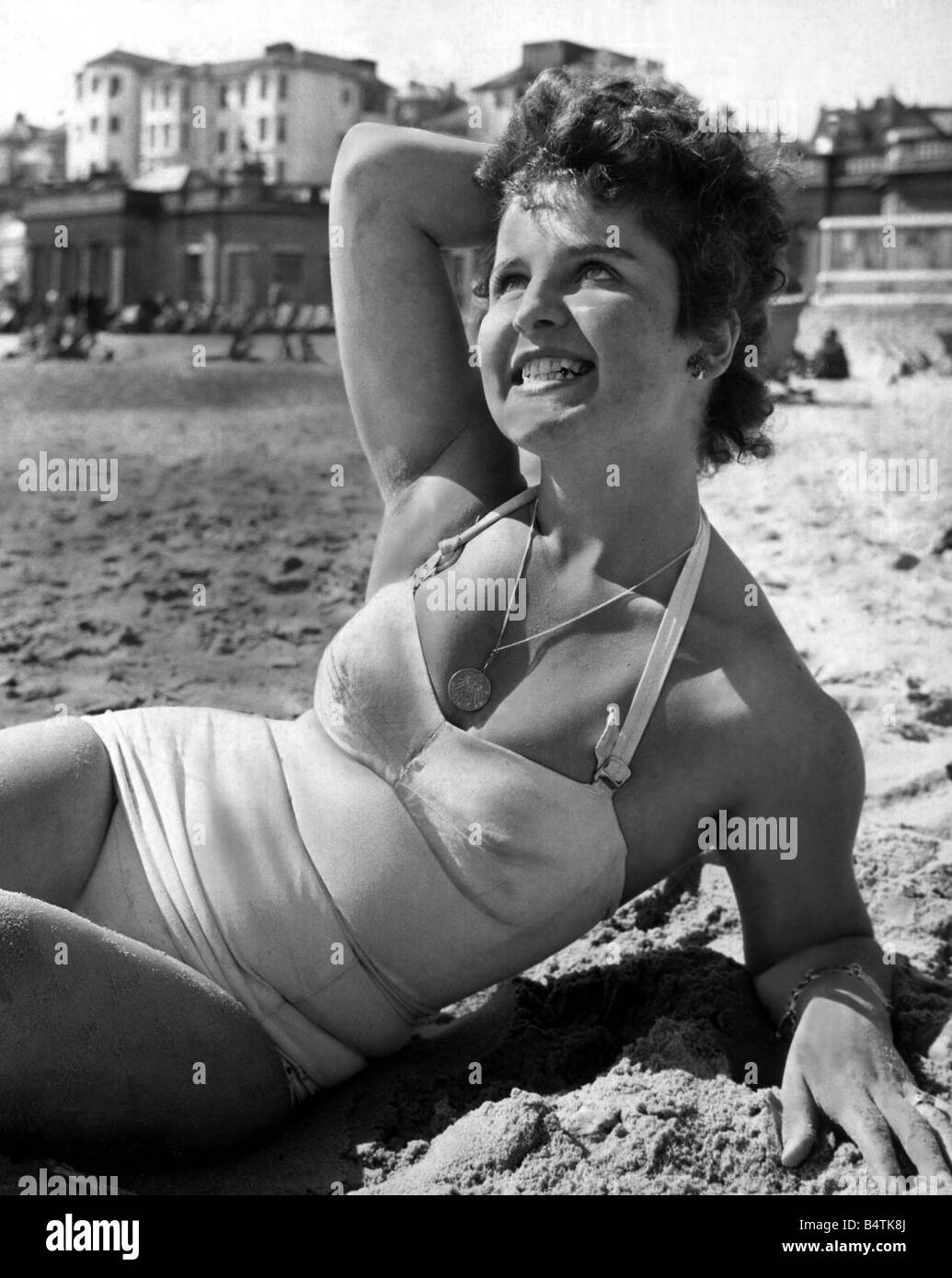 Beach babe Avril 1958 Le beau temps à Southampton brough Gitta Carmen Weiss à profiter du soleil sur la plage portant un costume de bain maillot de bain 1950 vêtements mode assis sur le sable avec son visage bouleversé au soleil mirrorpix Banque D'Images