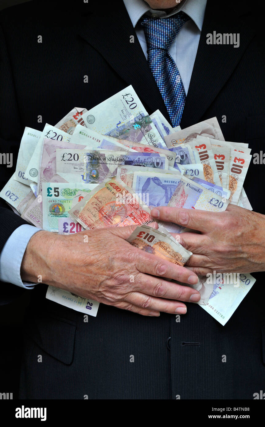 Homme d'affaires portant costume de bureau intelligent deux mains serrant piles UK livres sterling billets concept d'argent pour les banquiers gros chats cupidité hommes en costumes argent en main Banque D'Images