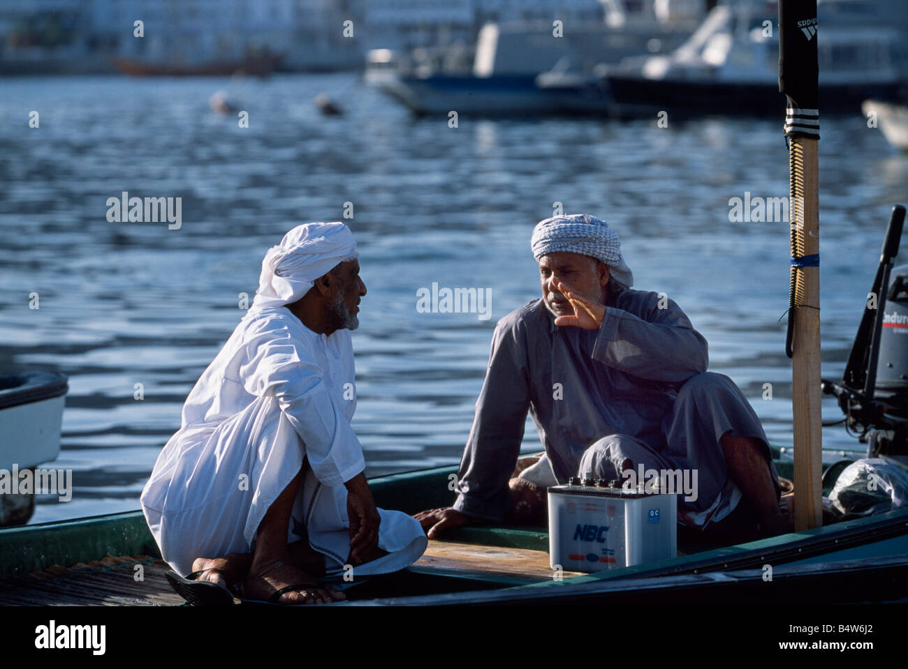 Oman, Muscat, Muttrah. Les pêcheurs se présentent sur leur bateau par le quai en face de Muttrah souq de poissons Banque D'Images