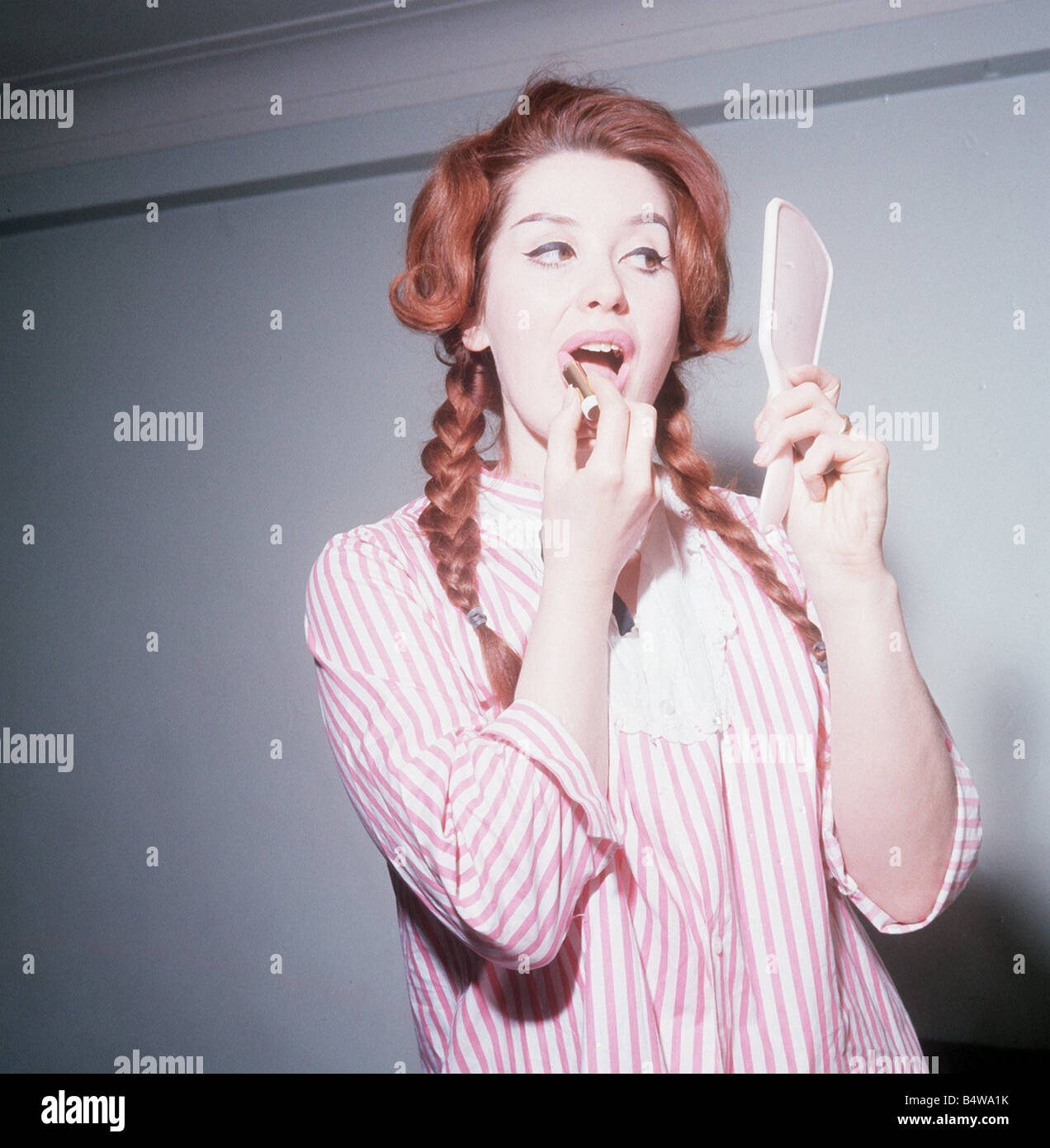 Heller Toren actrice modèle 1964 puting sur lipstick holding hand mirror  chemise rayée rose Photo Stock - Alamy