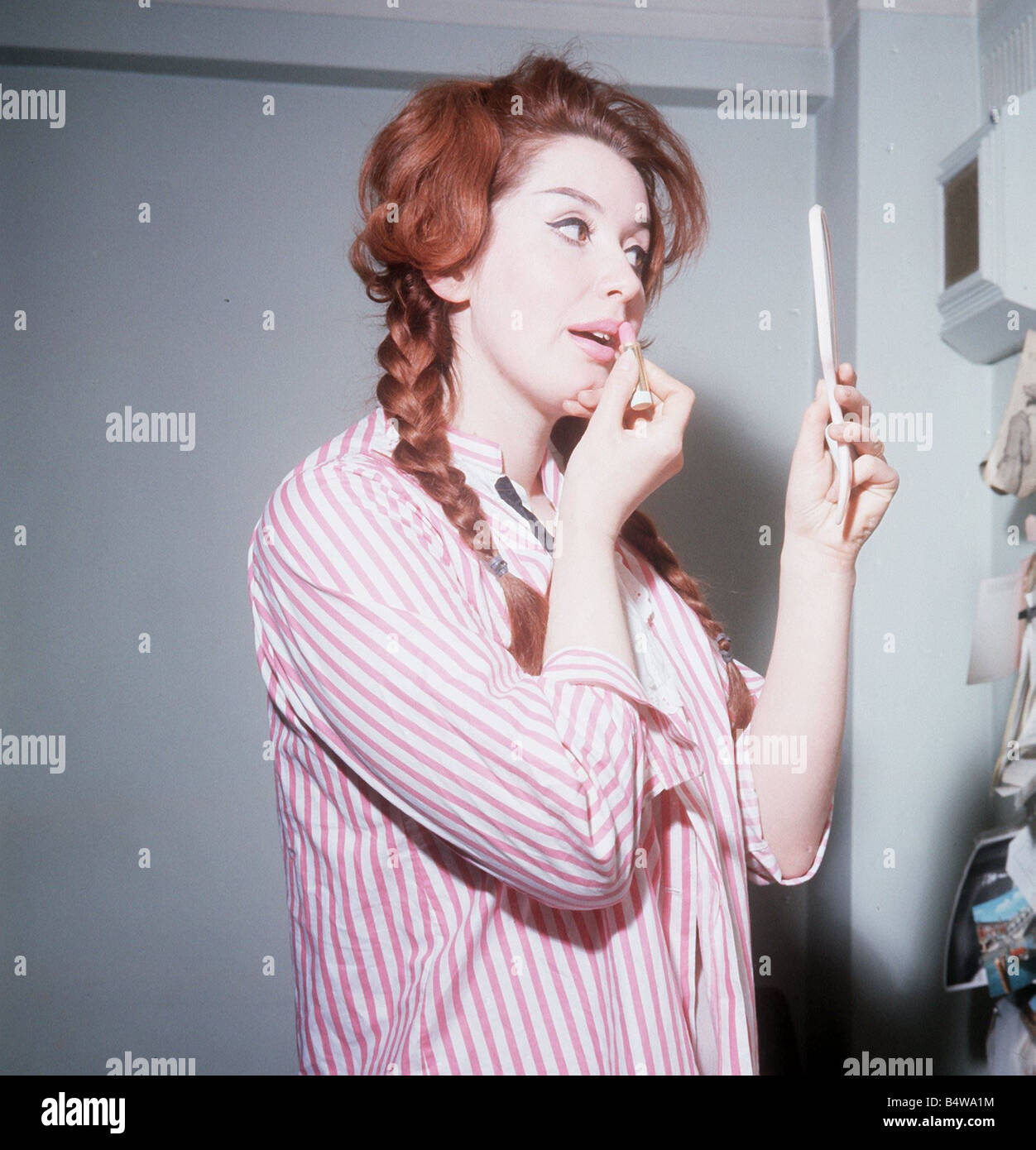 Heller Toren actrice modèle 1964 puting sur lipstick holding hand mirror  chemise rayée rose Photo Stock - Alamy