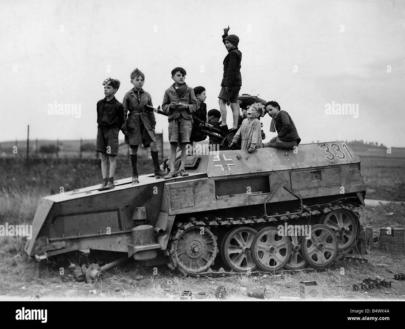 World War 2 1944 Les enfants jouent sur un éliminé la moitié allemand véhicule blindé à chenilles en Normandie Banque D'Images