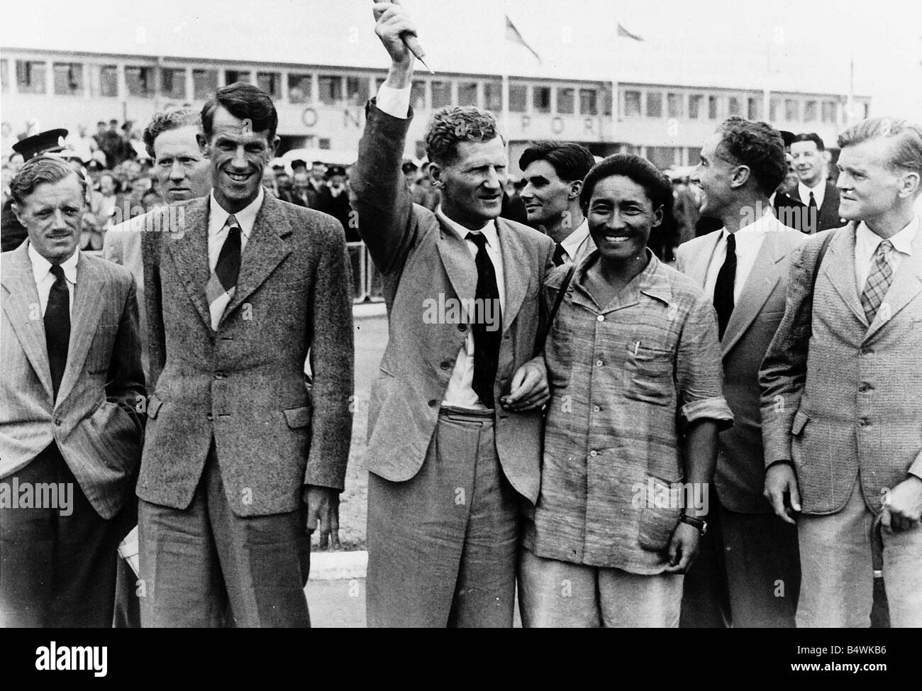 Les hommes de l'Everest les hommes de la mouche accueil expéditions britanniques sont arrivés à l'aéroport de Londres aujourd'hui après un délai de 24 heures dans l'avion a eu lieu en une nuit à Rome le parti comprend 42 ans Col John Hunt chef Edmund Hillary et le sherpa Tensing Tigre aussi entre la partie sont Mme Hunt Tensing s femme Angalammi et leurs filles Pember âgé de 16 et 14 ans à Nema Scène de l'aéroport de Londres montrant le héros alpinistes de l'Everest alors que le Col John Hunt leader est vu brandir le drapeau Union Jack qu'ils avaient fixé au Mont Everest Juillet 1953 P012560 Banque D'Images