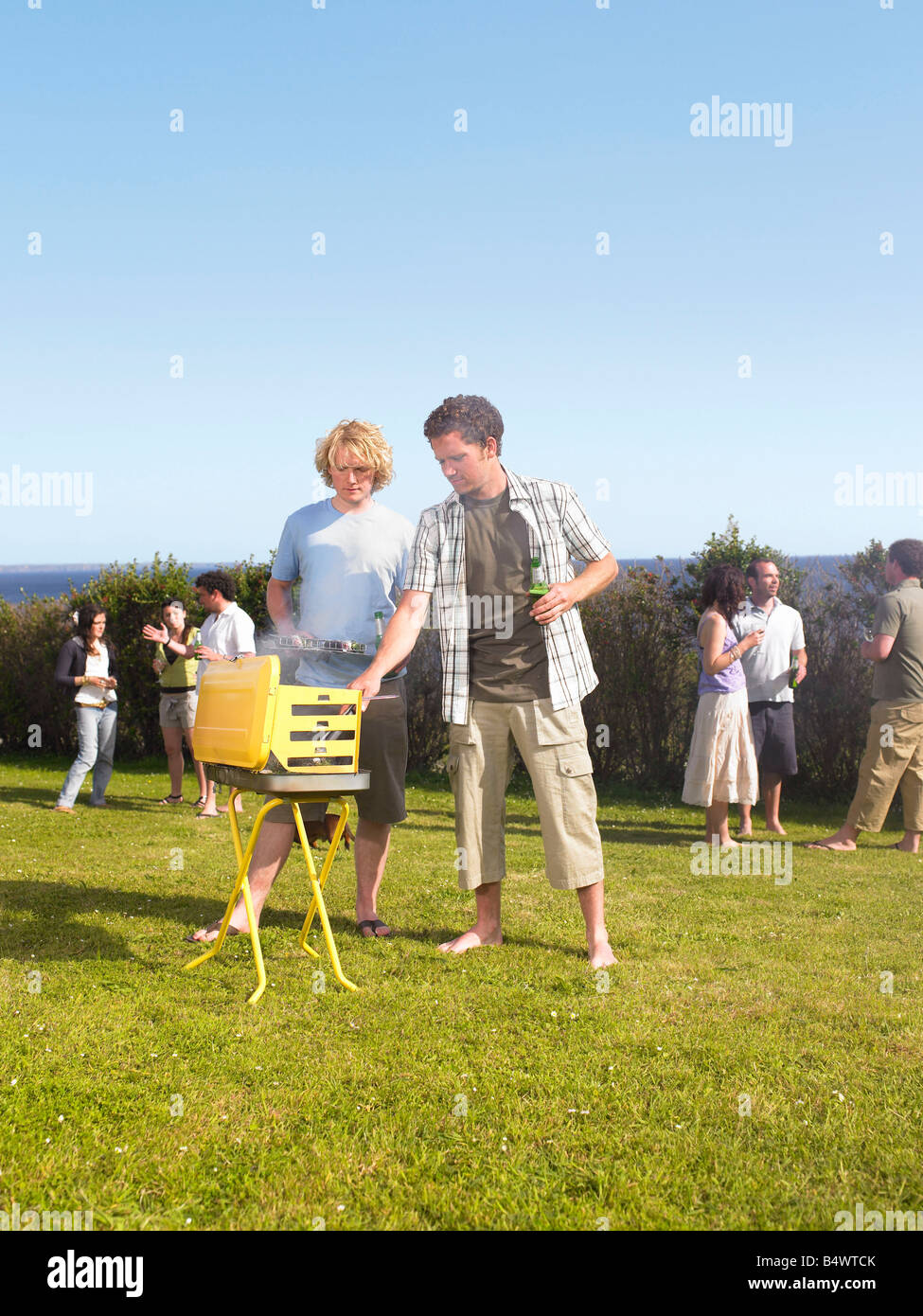 Man tending barbecue avec ami Banque D'Images