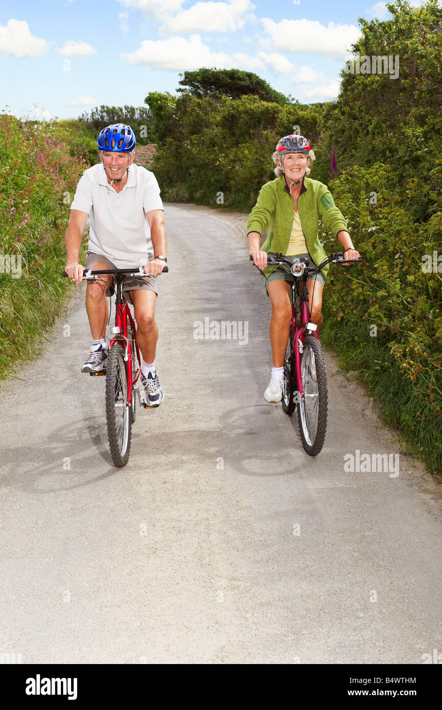 Senior couple cycling on country lane Banque D'Images