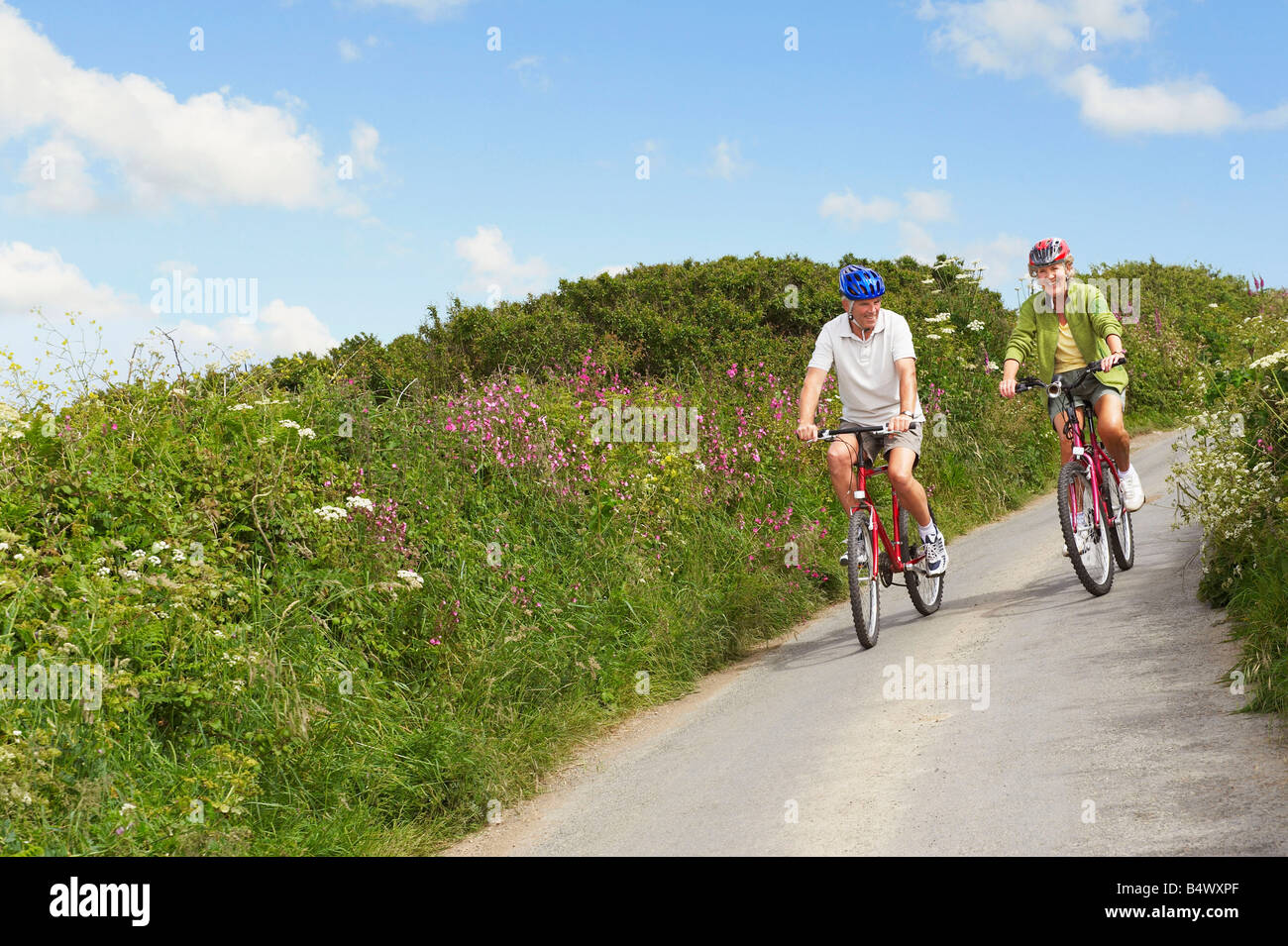 Senior couple cycling down country lane Banque D'Images