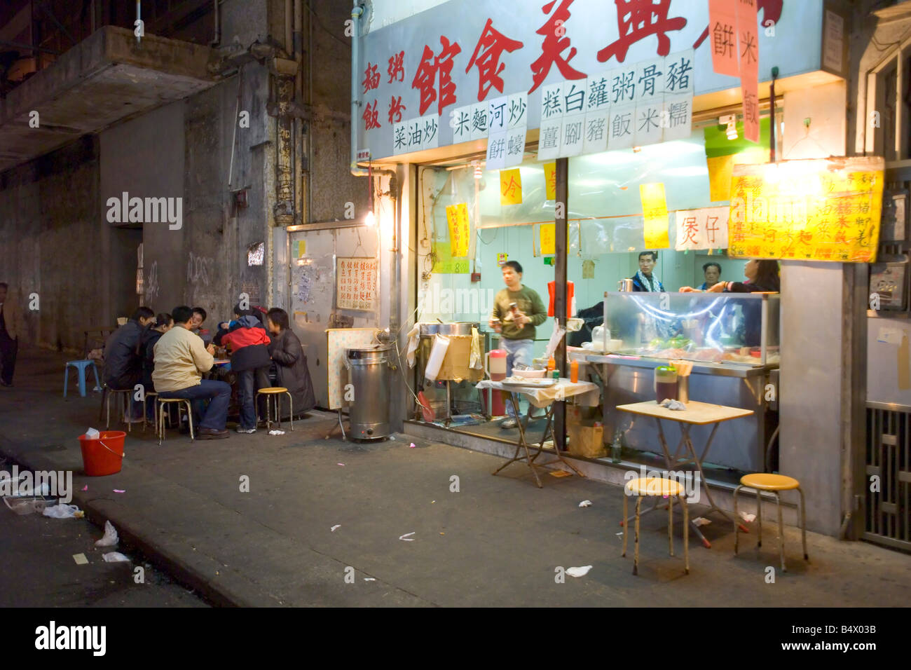 Une famille de Chinois de dîner à l'extérieur d'un petit restaurant sur le bord du trottoir de marché de Temple Street. Banque D'Images