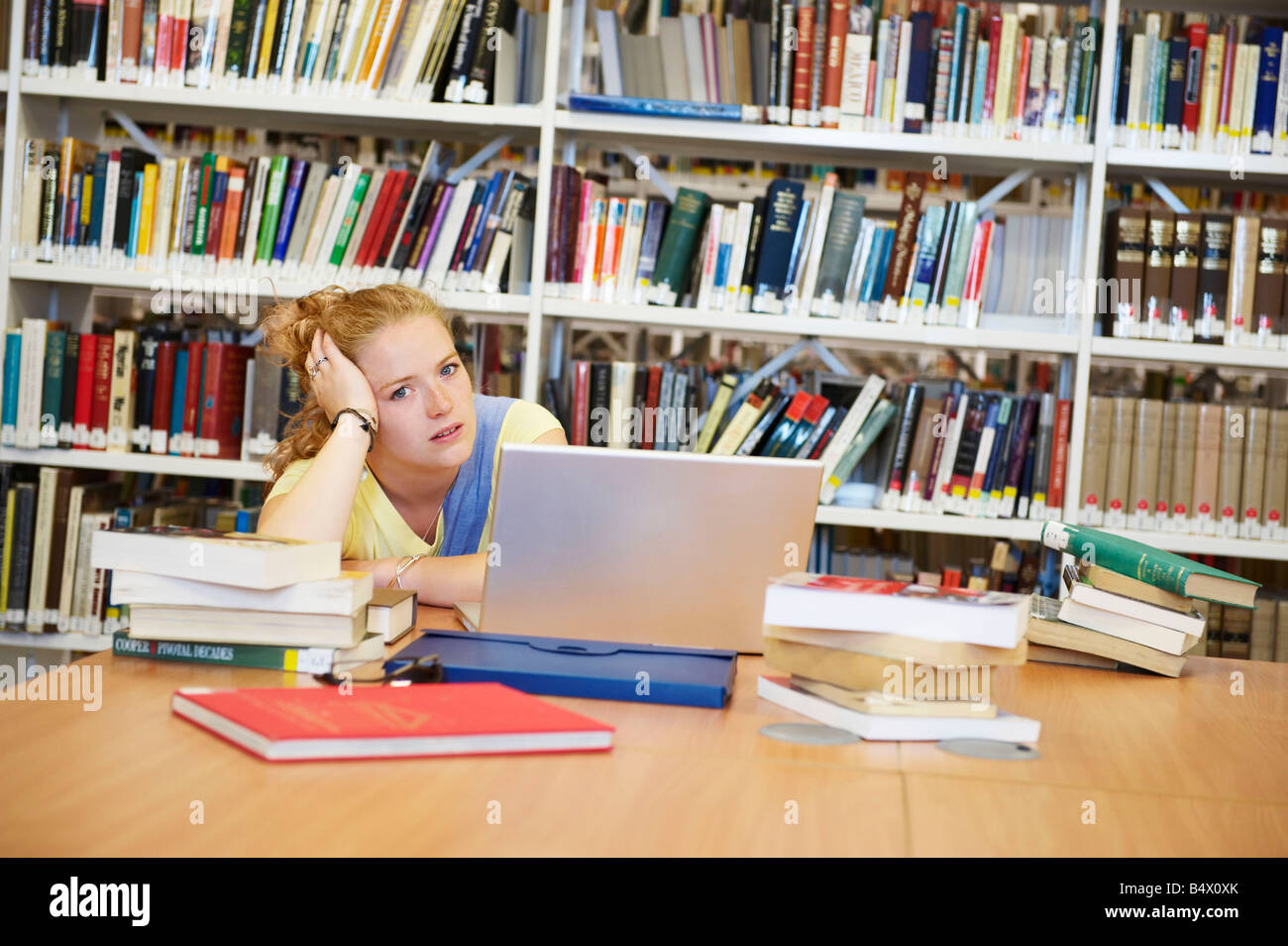 Jeune femme s'ennuie dans la bibliothèque Banque D'Images