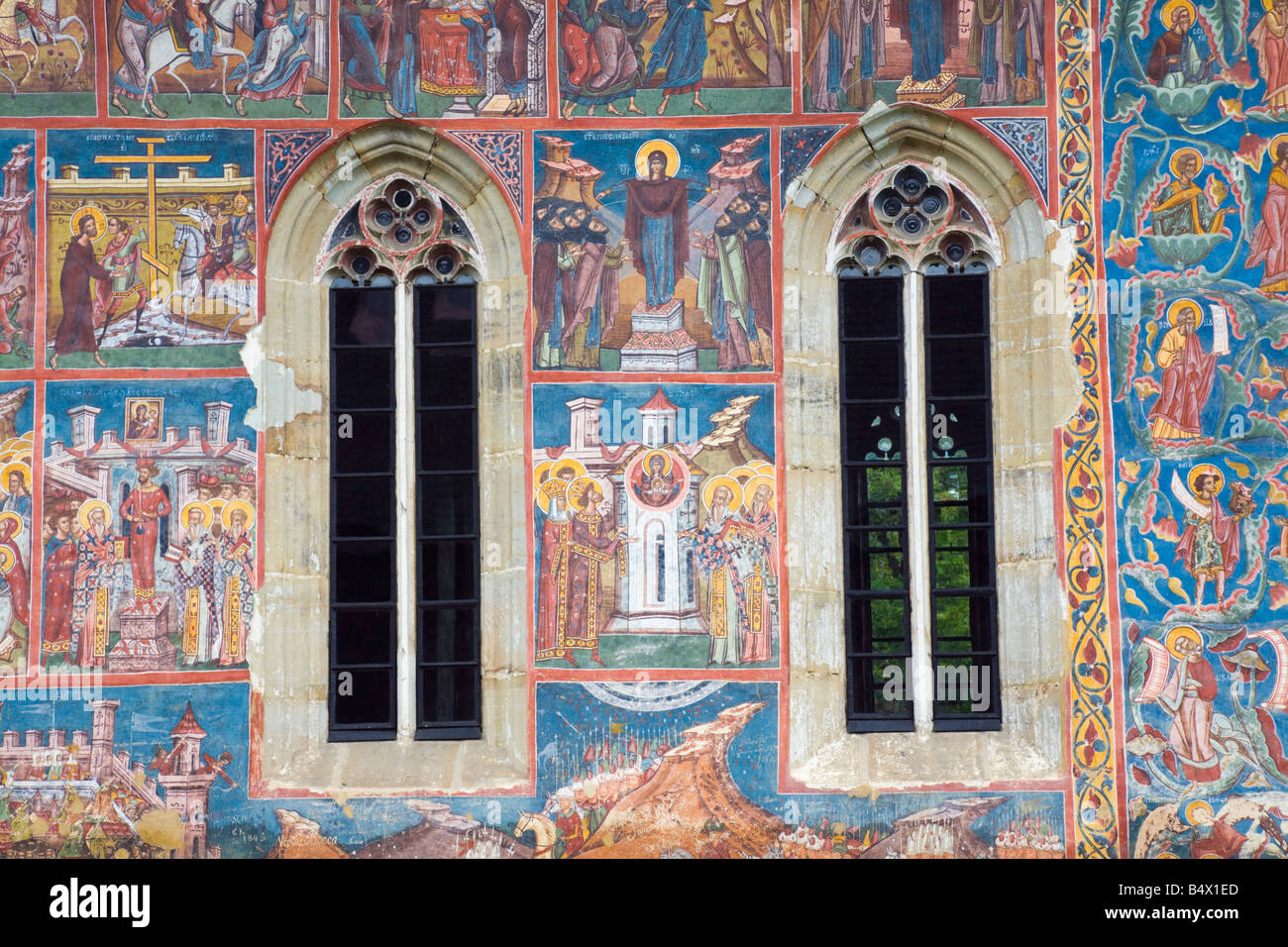 Des peintures religieuses sur les murs de l'église extérieure et deux fenêtres au monastère Moldovita. La Moldavie Bucovine Roumanie Europe Banque D'Images