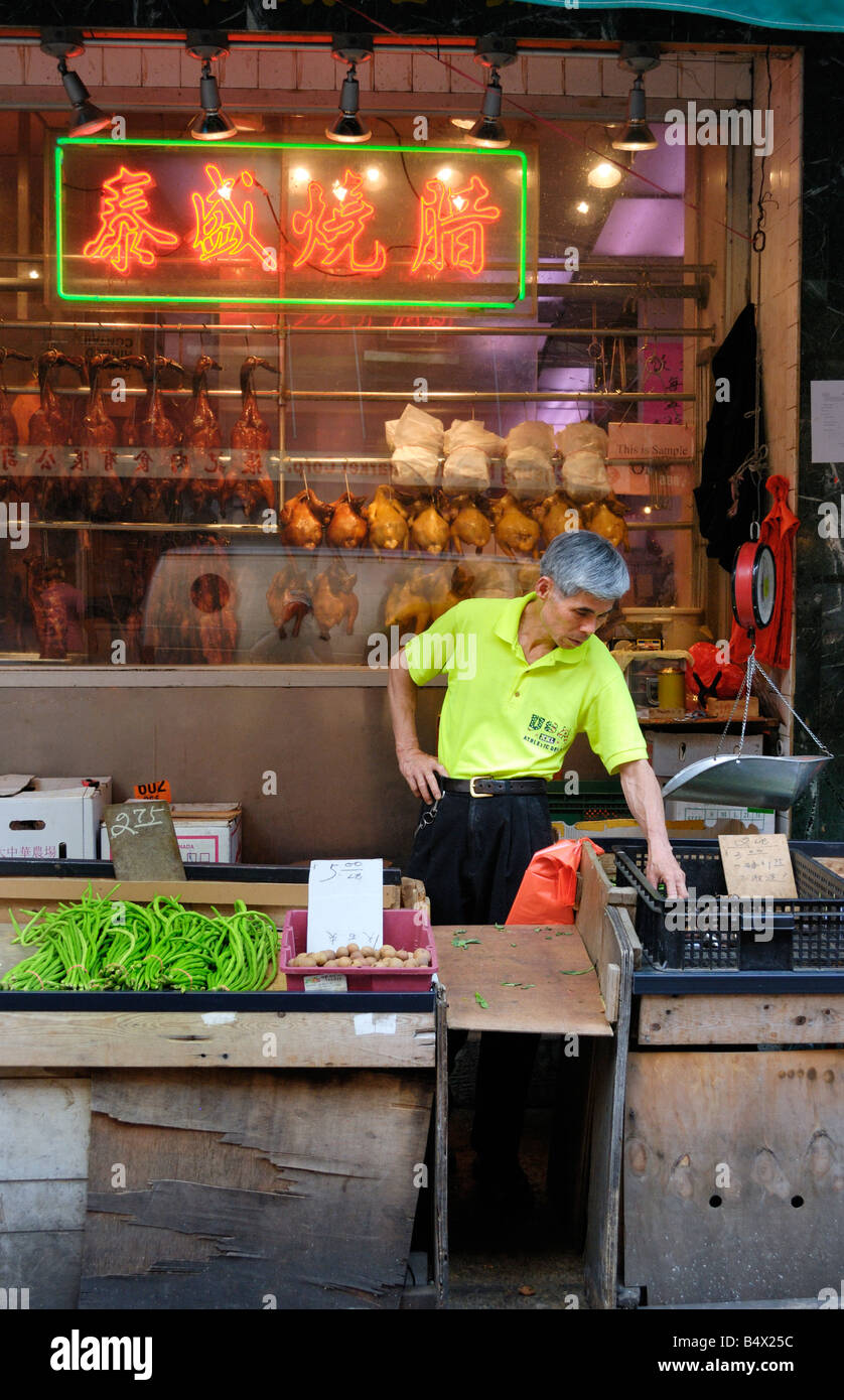 Un homme attend les clients à son stand de légumes sur Mott Street à New York Chinatown. Banque D'Images