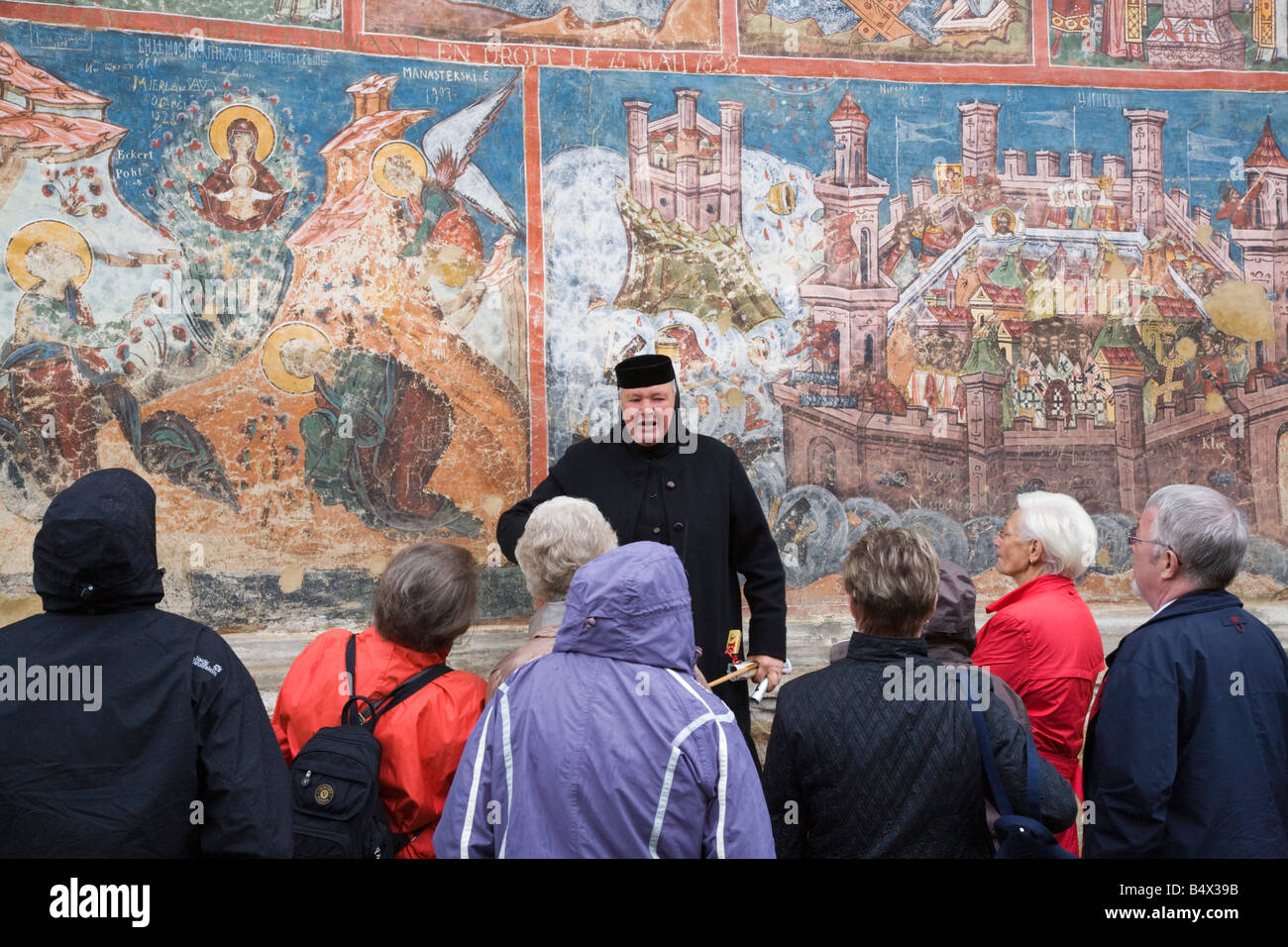 Groupe de touristes et Nun donnant visite guidée au Monastère Moldovita par peint mur extérieur. La Moldavie Bucovine Roumanie Europe Banque D'Images