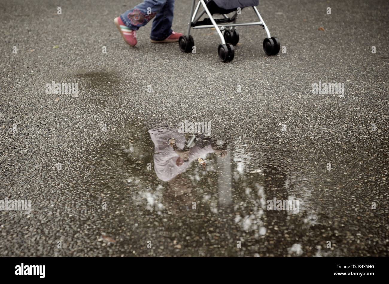 La réflexion de l'enfant en flaque poussant poussette après la pluie à Brooklyn New York USA Banque D'Images