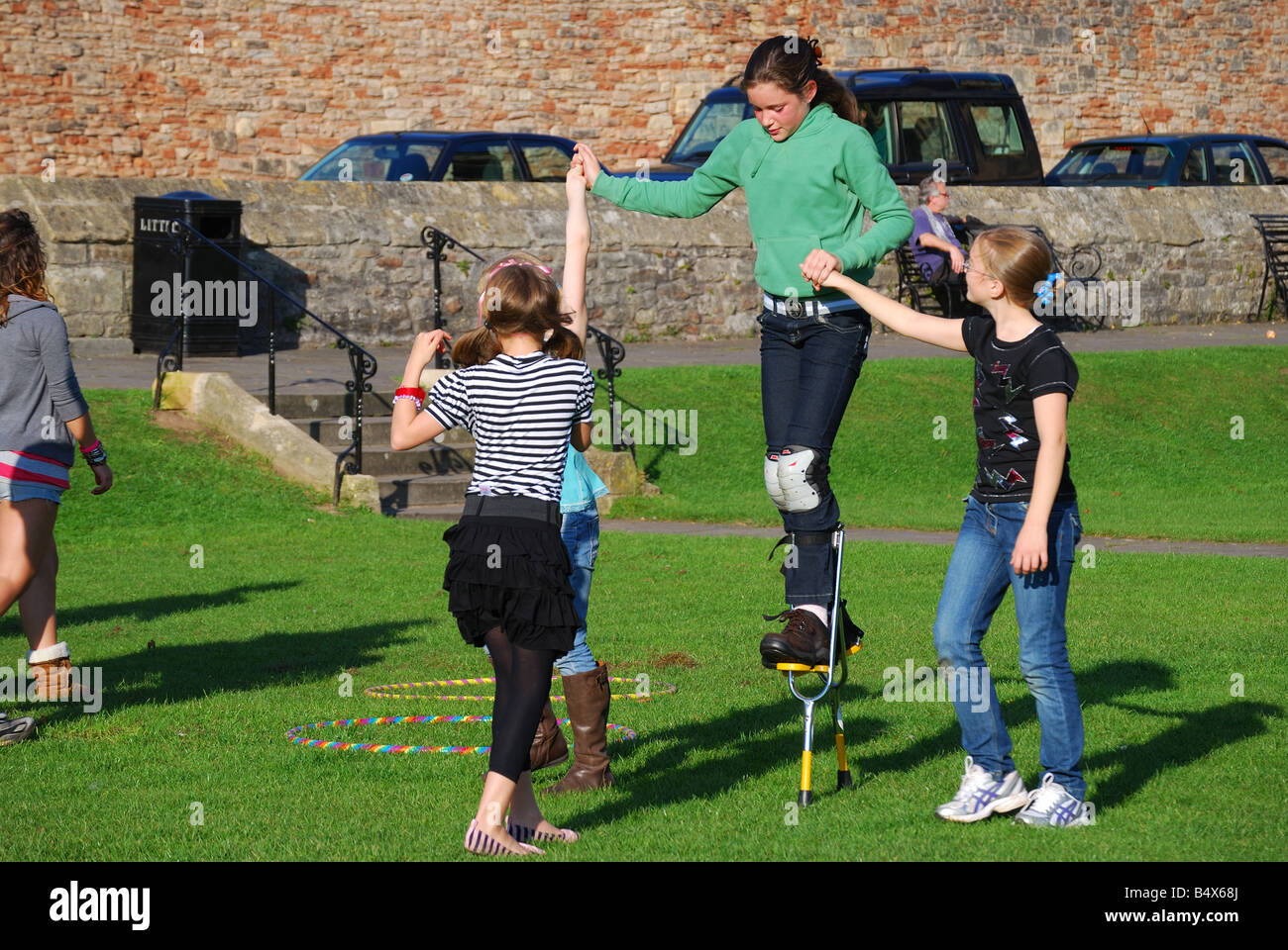 De jeunes filles, jouant sur des échasses, Cathedral Green, Wells, Somerset, England, United Kingdom Banque D'Images