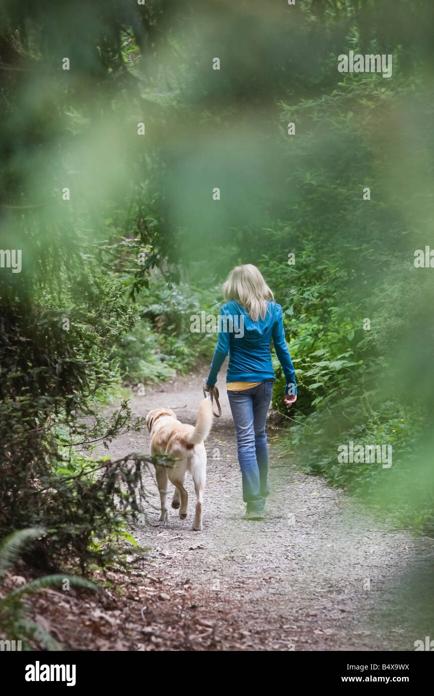 Girl walking dog sur chemin forestier Banque D'Images