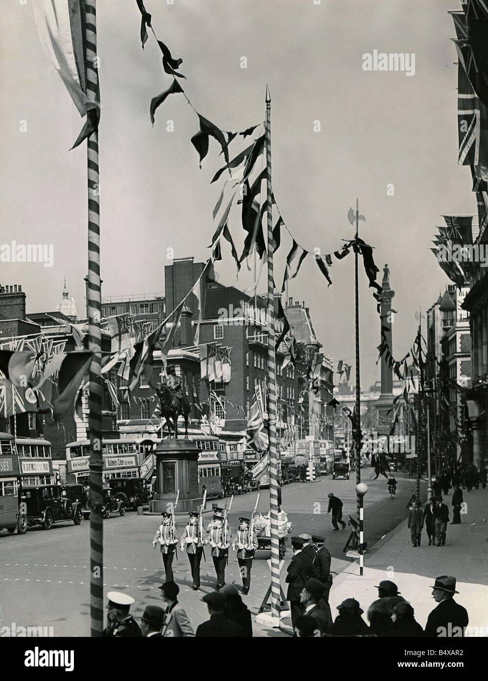 Whitehall décoré de drapeaux et banderoles en préparation pour le couronnement du roi George VI Soldiers marching avec Nelson Colonne s derrière eux Banque D'Images