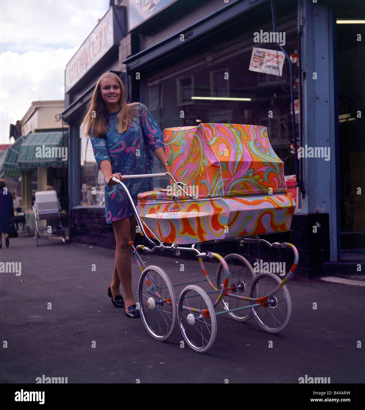 La mode des années 60 années 60 les vêtements Pschedelic paisley pram avec  femme blonde produit par Latitude enfant pour la Pram voir marcher dans la  rue avec la poussette de bébé