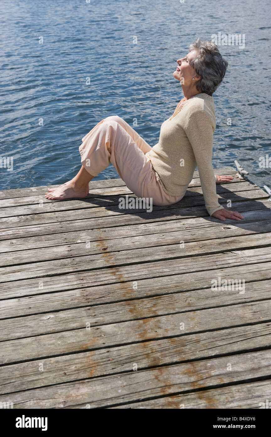 Senior woman sitting on dock Banque D'Images