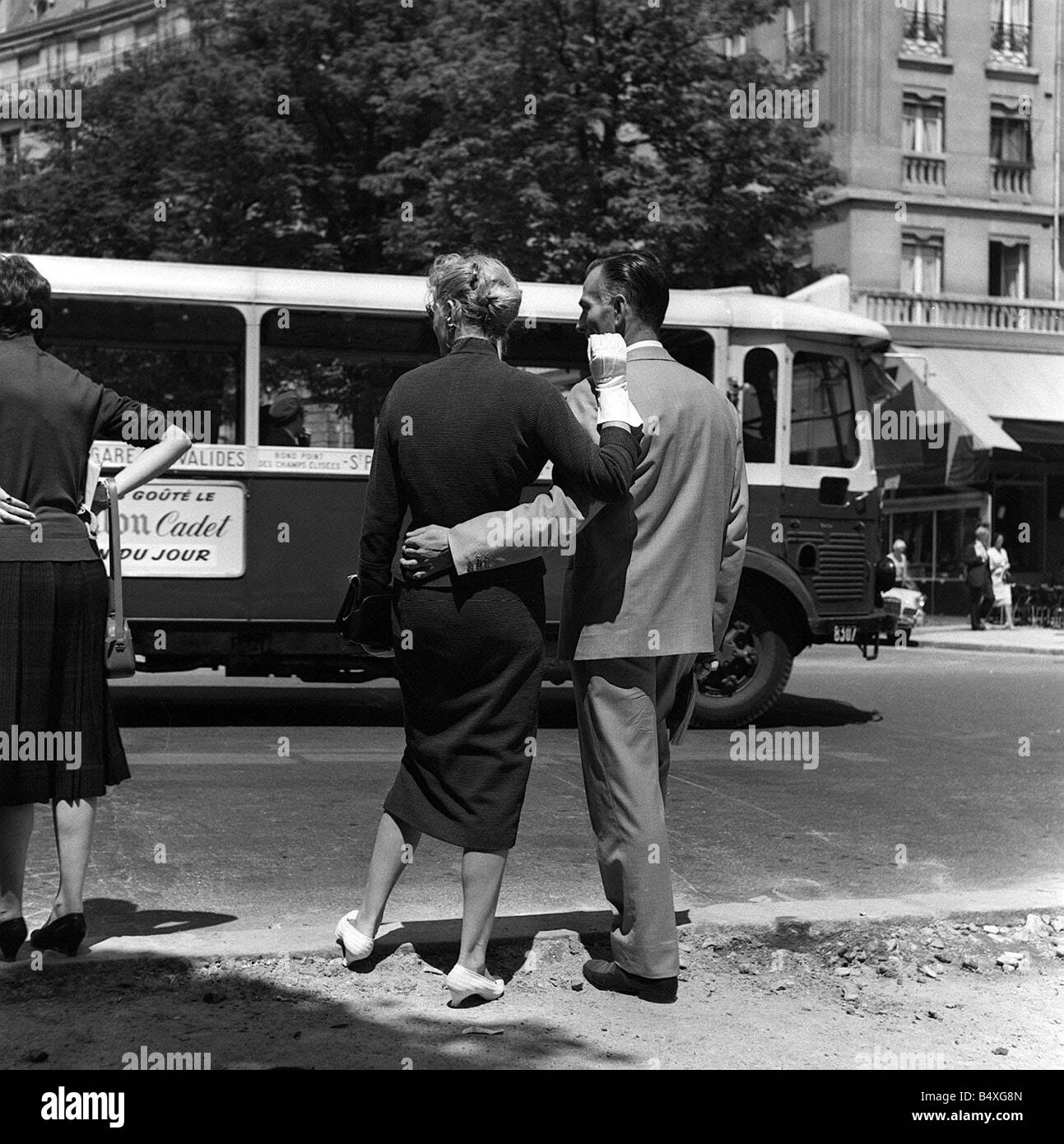 France Paris un homme avec son bras autour de la taille de sa petite amie attend pour traverser la route qu'un bus passe au cours de l'état d'urgence 1958 Banque D'Images