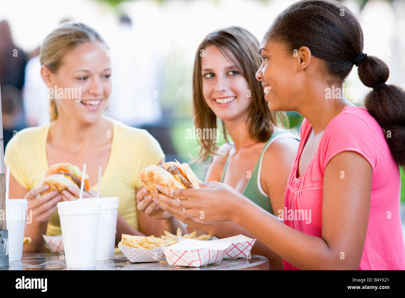 Teenage Girls Sitting Outdoors Eating Fast Food Banque D'Images