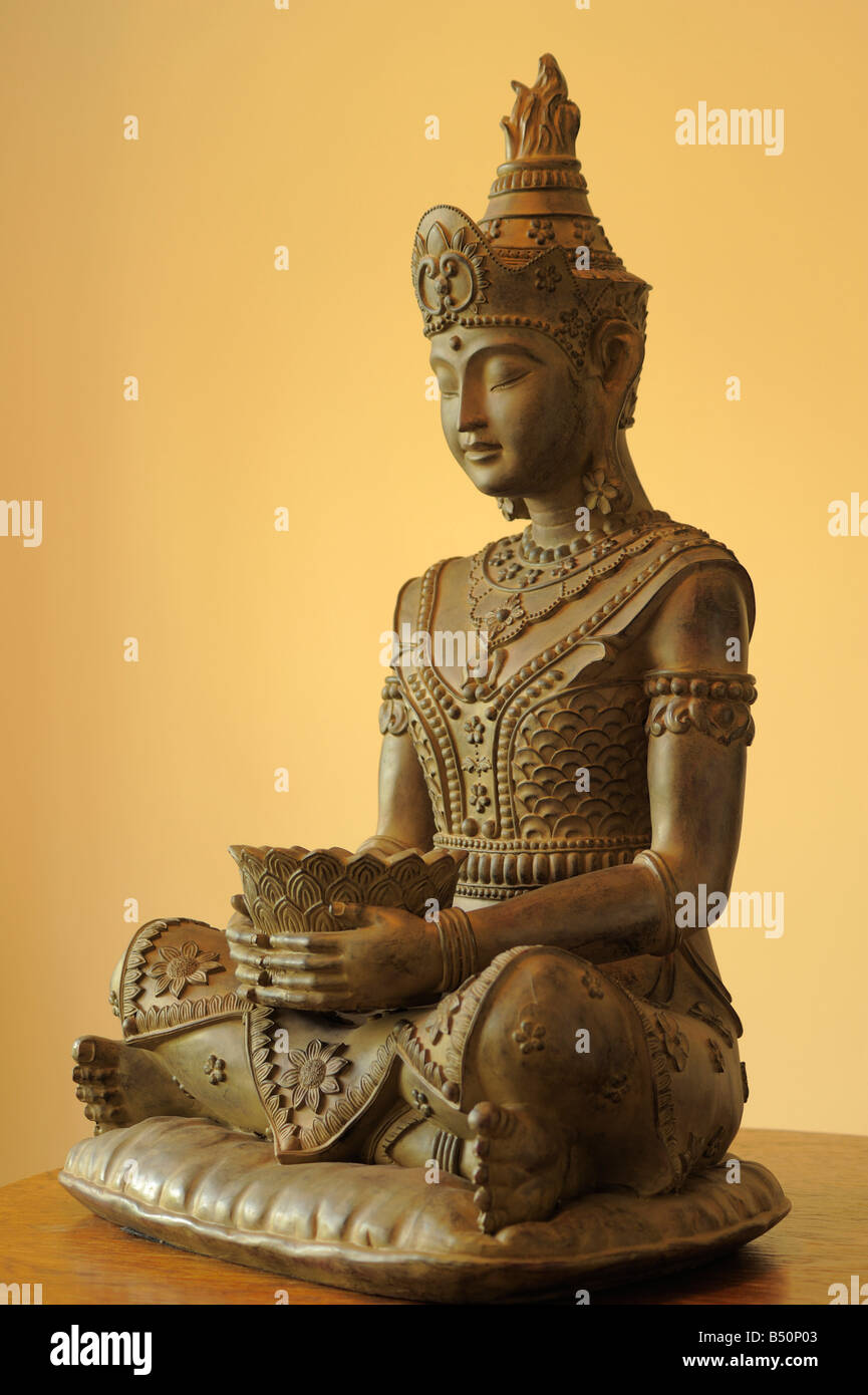 Statue en bois sculpté à la main de Bouddha assis en tailleur tenait un bol contre un fond uni Banque D'Images