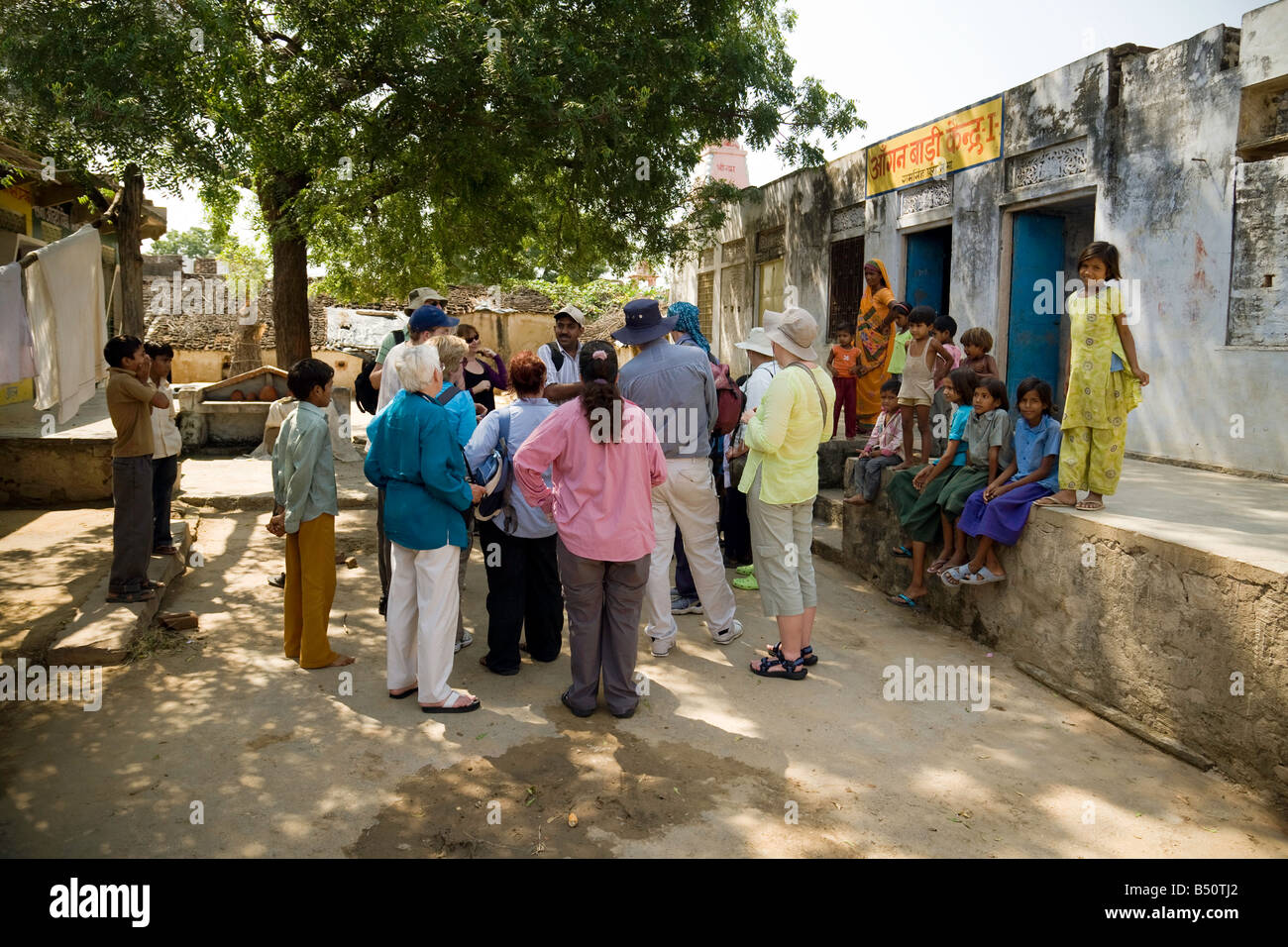 Les touristes de l'Ouest ont une visite guidée avec un guide autour d'un village indien, regardé par les enfants ; Rajasthan, Inde Banque D'Images