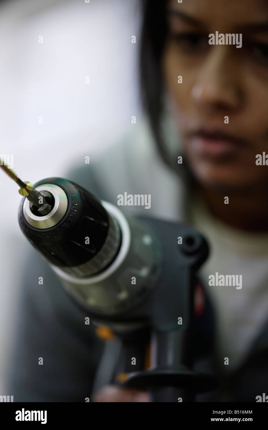 Femme Asiatique utilise la perceuse électrique à conduire dans une vis à bois Banque D'Images