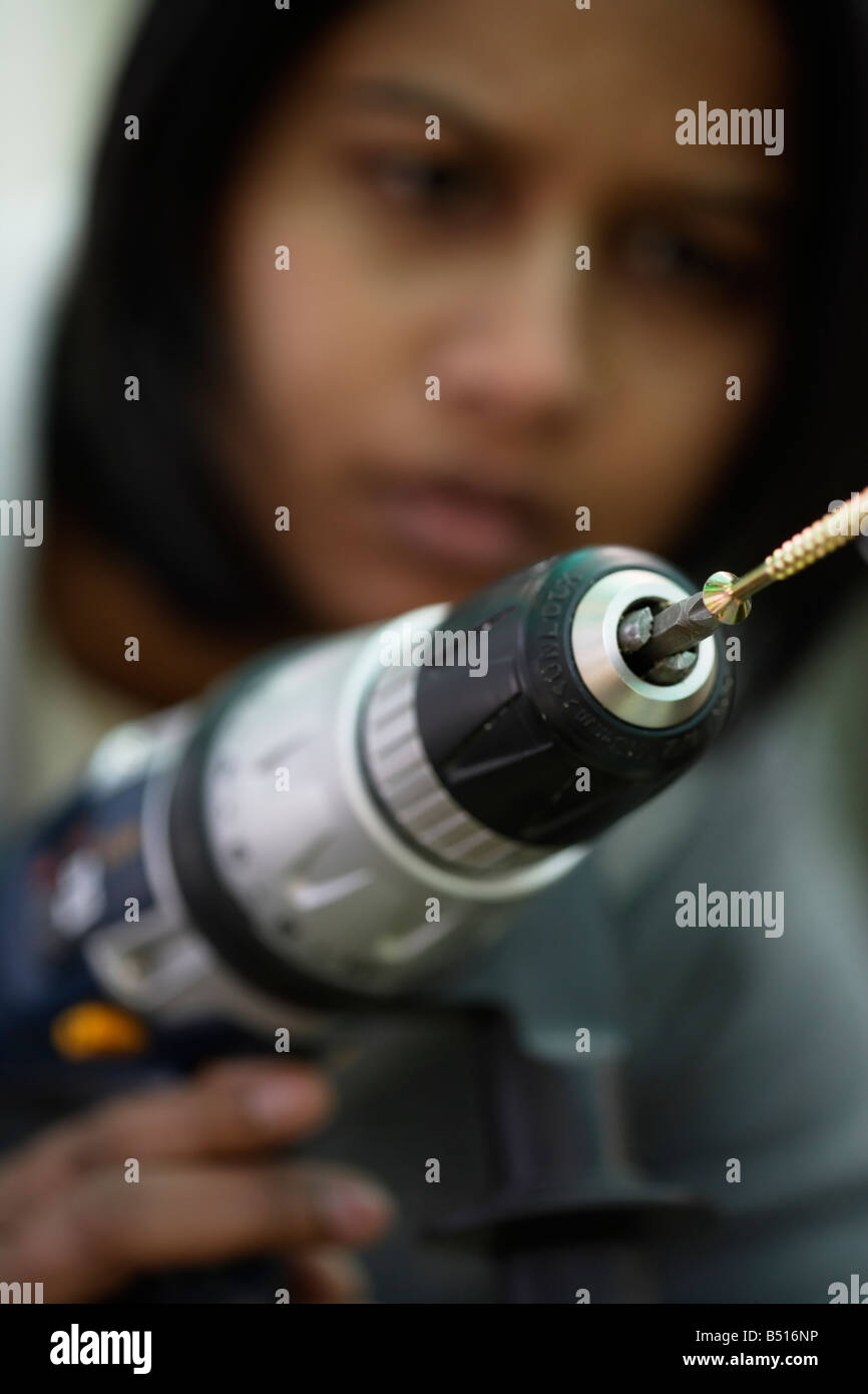 Femme Asiatique utilise la perceuse électrique à conduire dans une vis à bois Banque D'Images