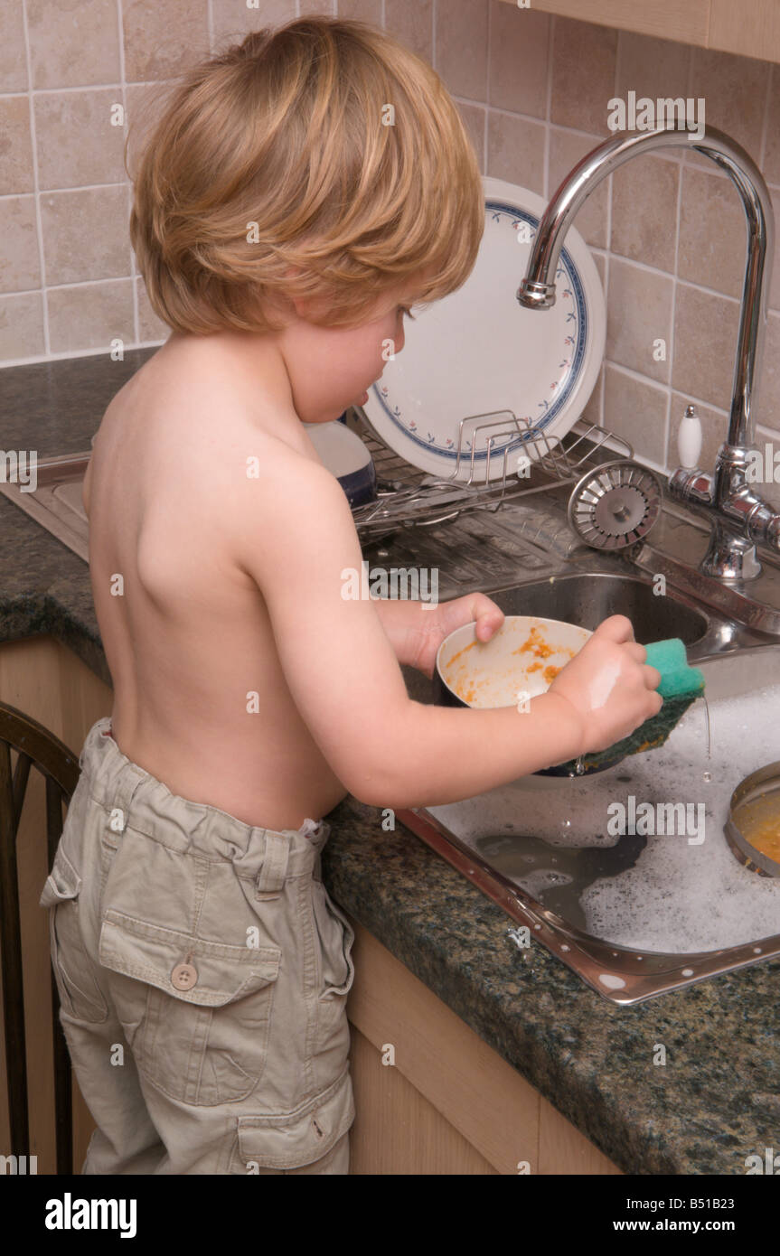 Bébé garçon enfant de l'évier de la cuisine en faisant la vaisselle avec  eau chaude robinet ouvert Photo Stock - Alamy