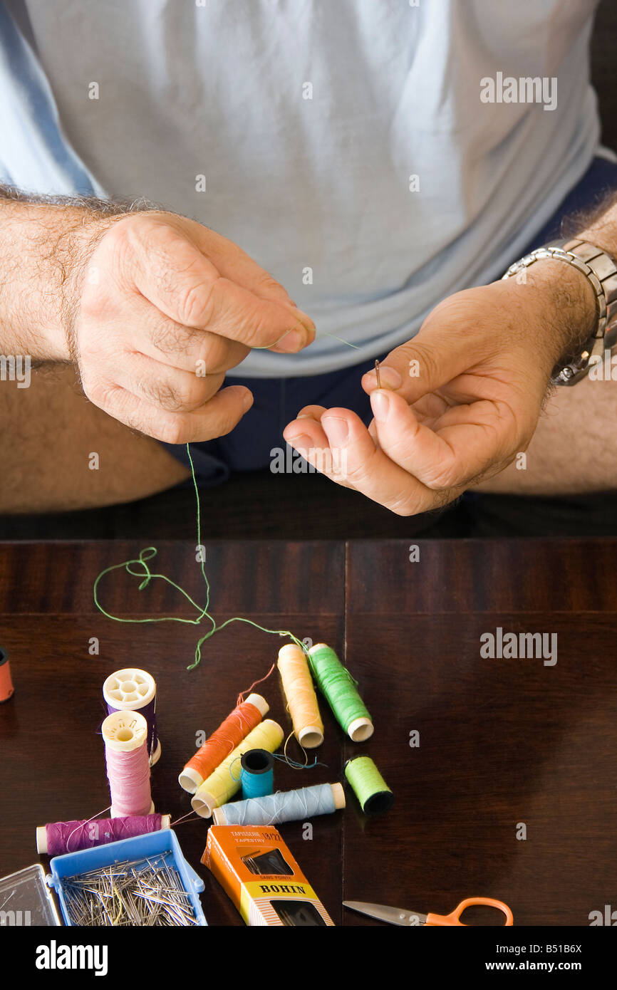 Les mains de l'aiguille enfilage Mans avec green cotton Banque D'Images