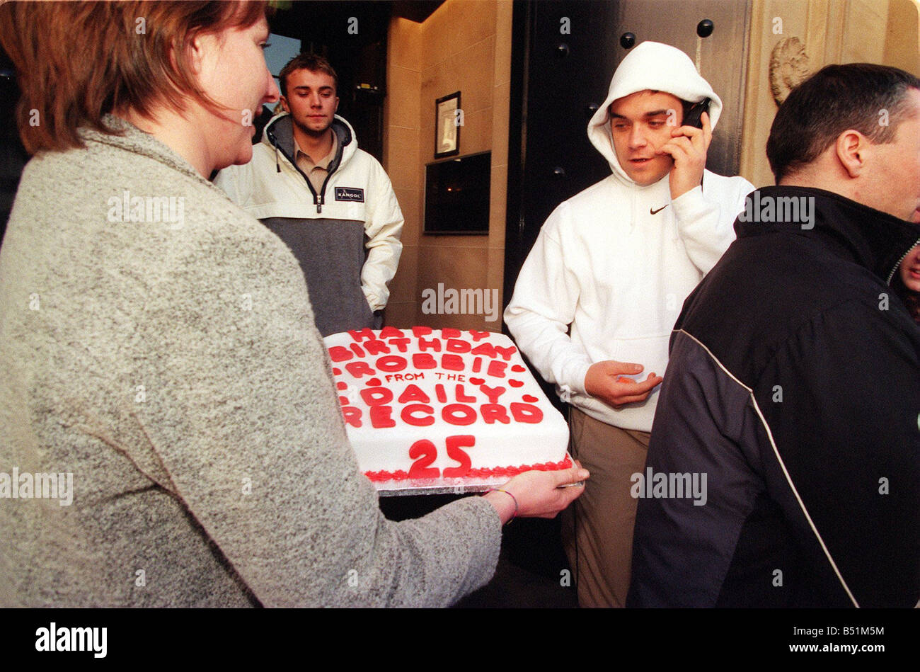 Robbie Williams fait un 25e anniversaire gâteau de Margaret Mallon Février  1999 pendant qu'il marche par talking on mobile phone wearing hooded top  Nike Photo Stock - Alamy