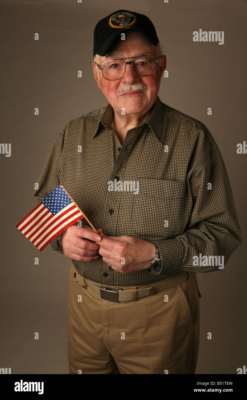 Personnes âgées American World War II ancien combattant tenant un drapeau américain et portant un chapeau de l'armée des États-Unis. Banque D'Images