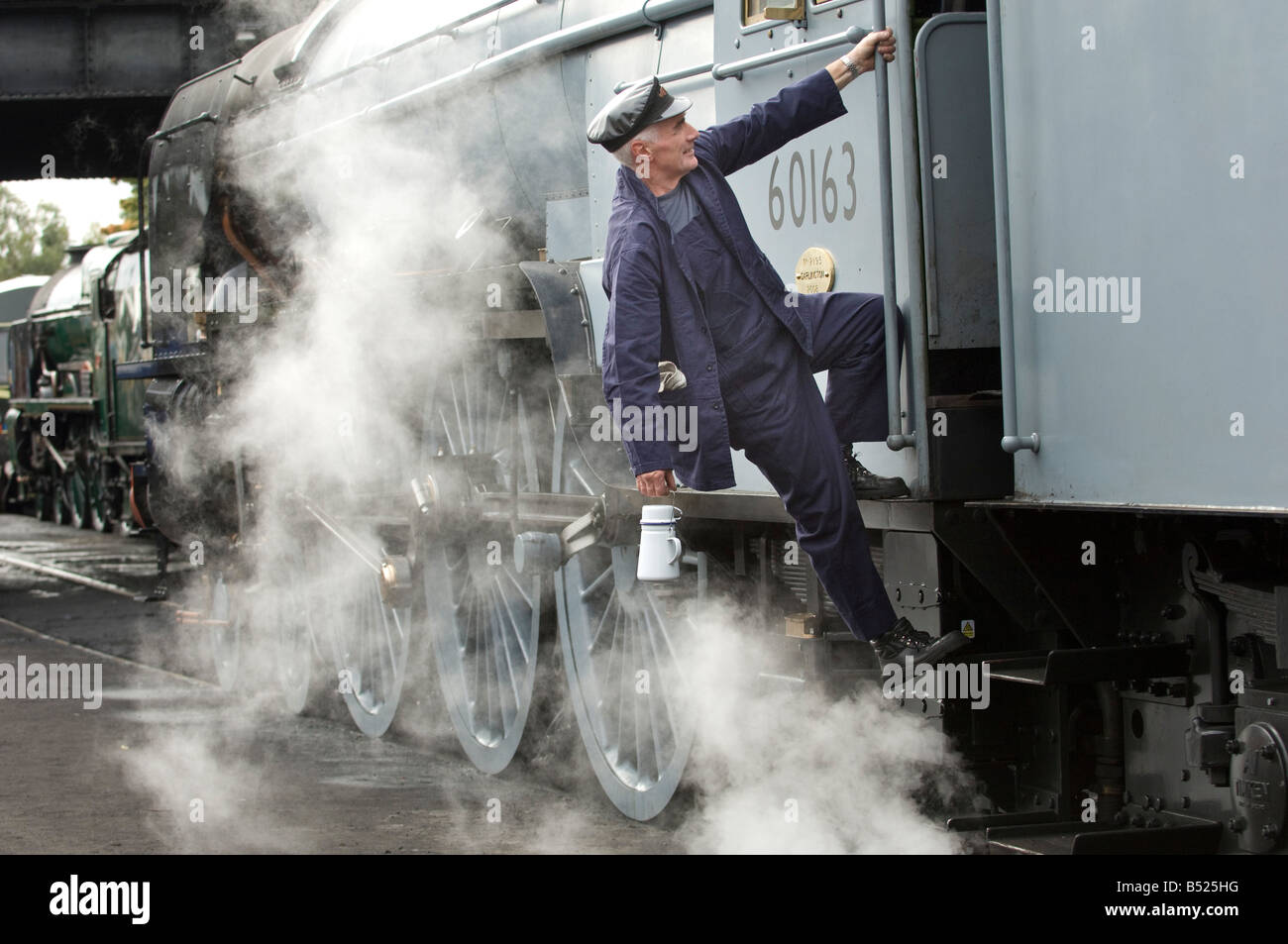 Un moteur à vapeur conducteur monte dans sa cabine. Le train est 60163 tornade, sur la Great Central Railway. Banque D'Images