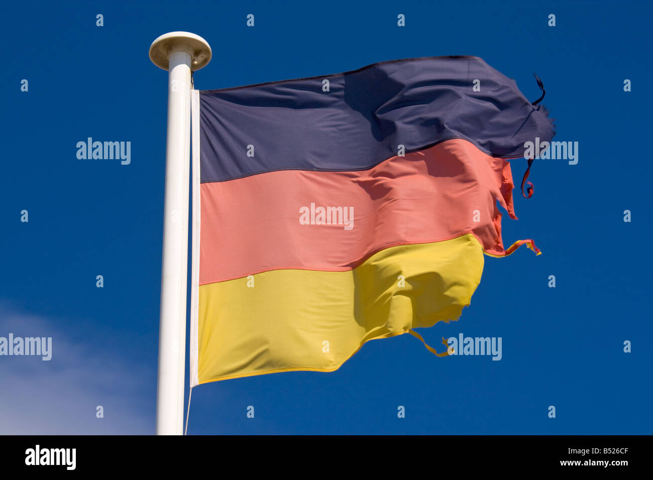 Un drapeau allemand en lambeaux de vagues dans le vent Banque D'Images