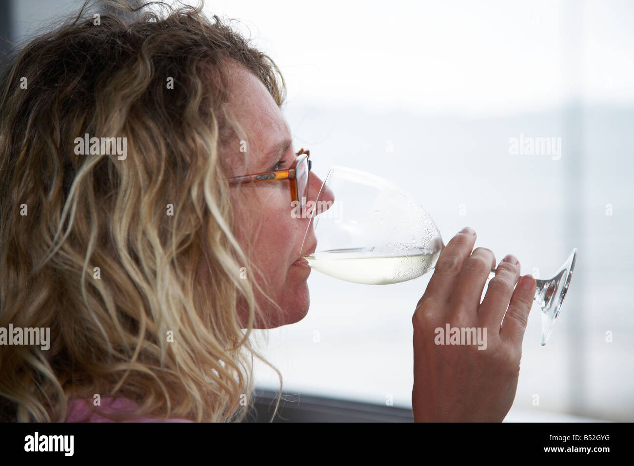 Femme en sirotant un verre de vin sur le balcon avec vue sur la mer Banque D'Images