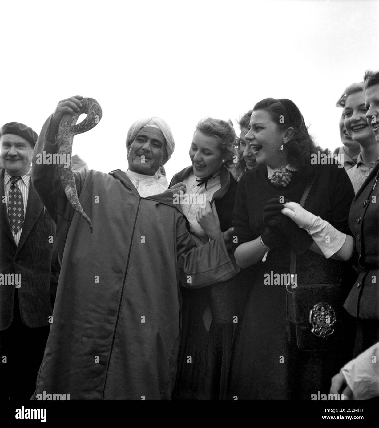 Un homme montre un serpent à un groupe d'actrices françaises fasciné au cours de leur visite à 'marrakech' maroc, Décembre 1952 Banque D'Images