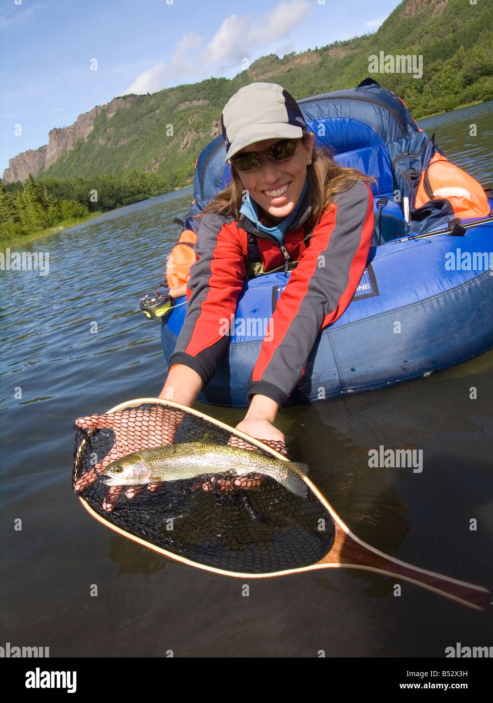 Pêcheuse à la mouche en float tube holding la truite dans le bénéfice net sur le lac Weiner dans Southeast Alaska summer Banque D'Images