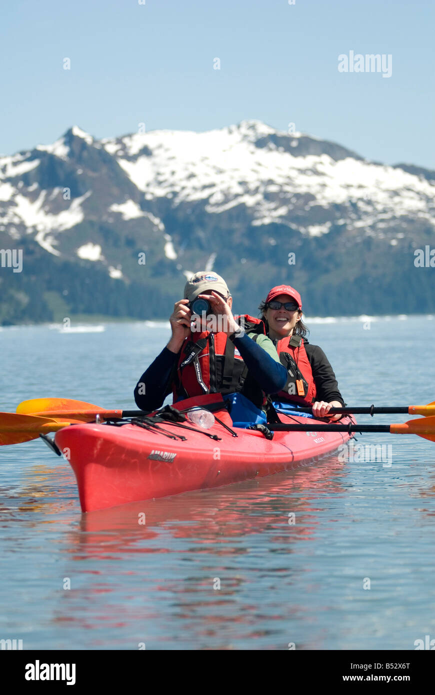 Paire de kayakistes prendre une photo comme ils Pagayez à travers Aialik Bay à Kenai Fjords National Park Summer Péninsule Kenai Banque D'Images